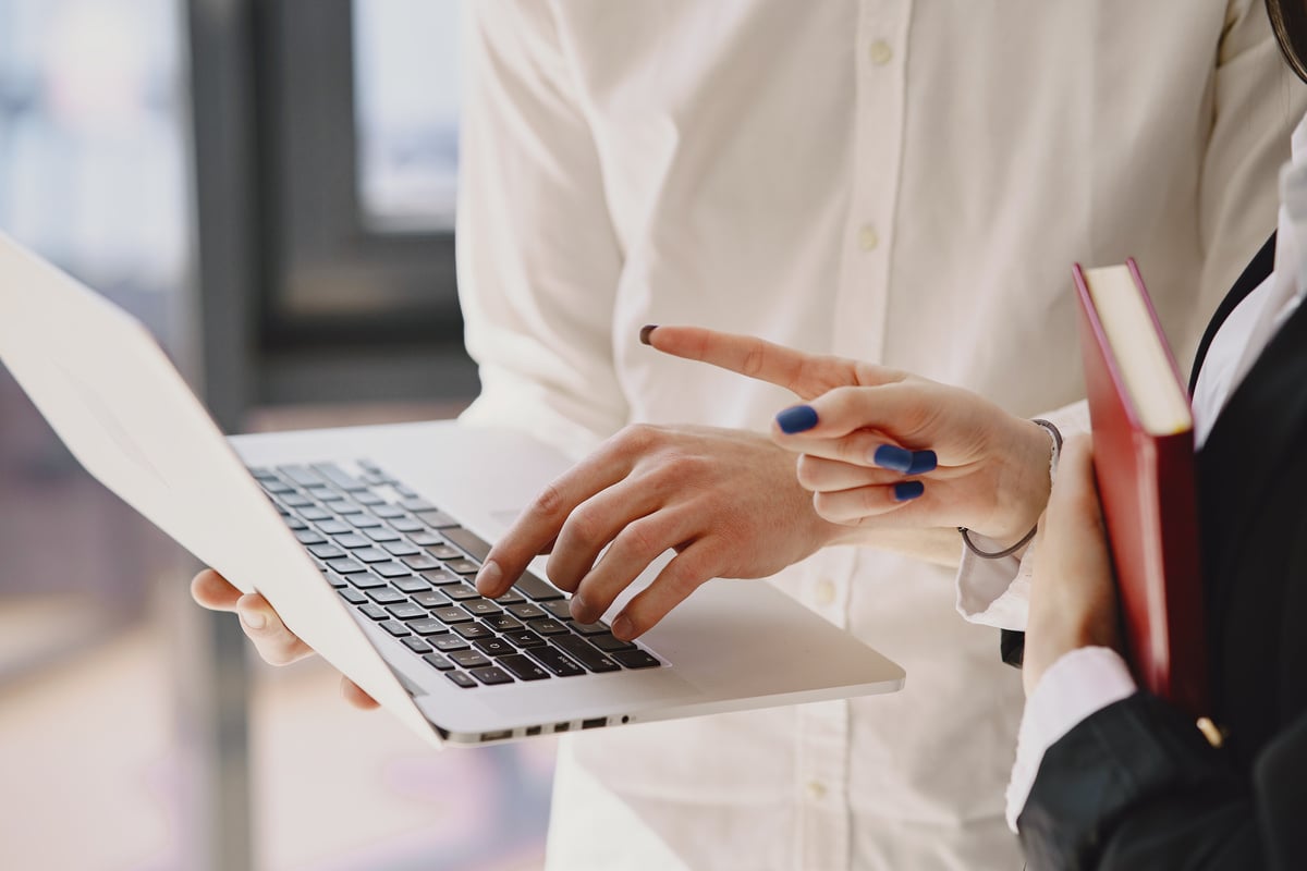 Crop unrecognizable man typing on laptop near female colleague